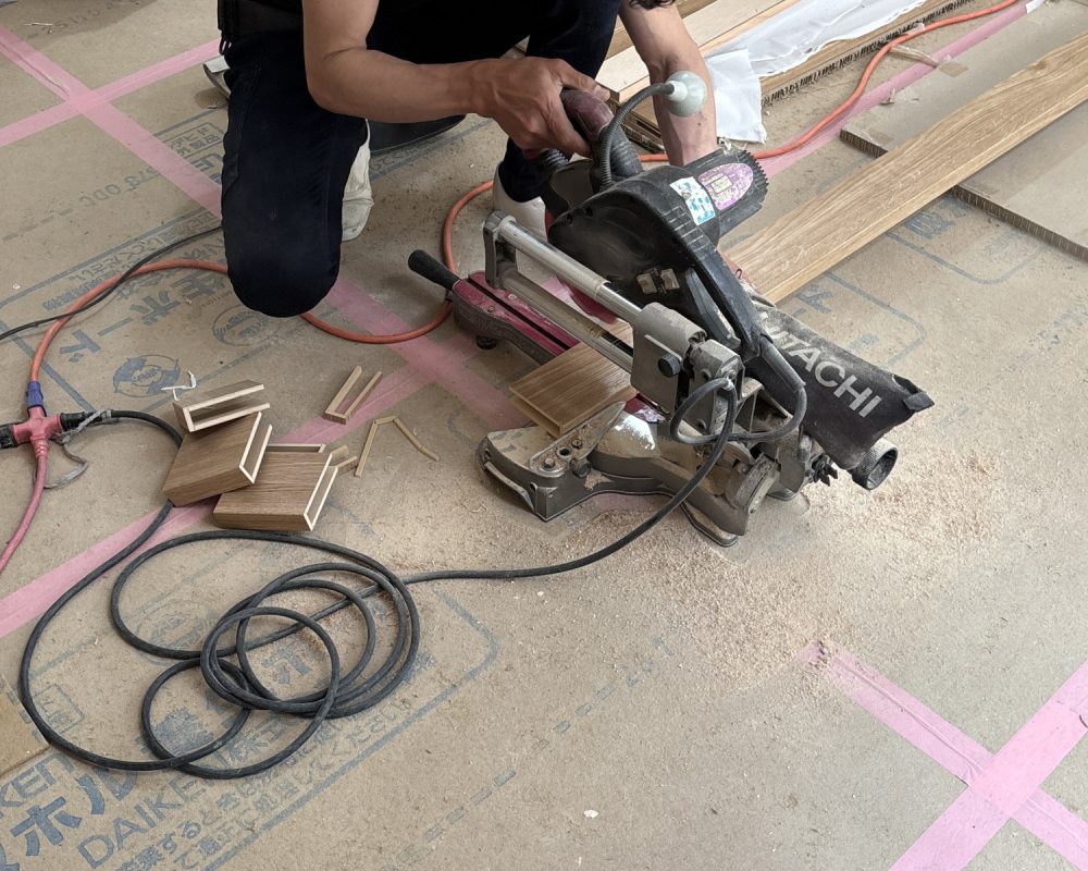 キッチン天井へ取り付けるルーバー材を、スライド丸ノコで正確にカットする施工風景。